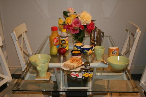 Amy's House Bed & Breakfast في Auburn: طاولة زجاجية عليها مزهرية بها زهور وطعام