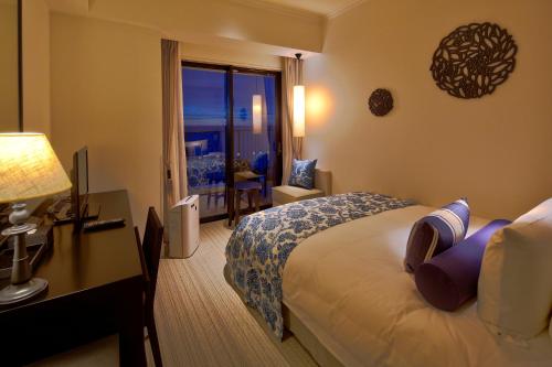 a hotel room with a bed and a desk and a window at Hotel Monterey Okinawa Spa & Resort in Onna