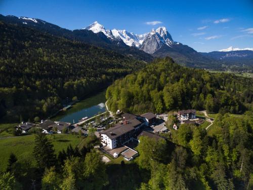 an aerial view of a house with a lake and mountains at Riessersee Hotel in Garmisch-Partenkirchen