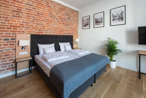 a bedroom with a large bed with a brick wall at Aparthotel BC 29 Residence in Krakow