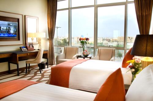 a hotel room with two beds and a desk and a window at Bayat Hotel in Khamis Mushayt