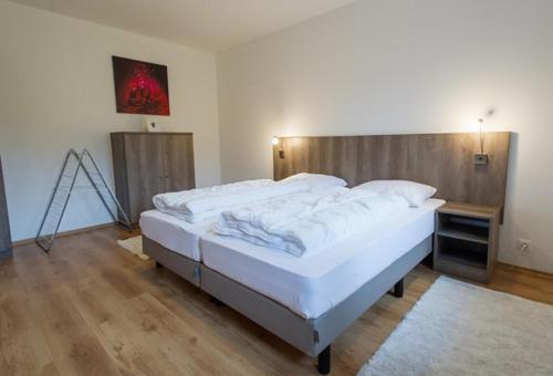 Schlafzimmer mit einem großen Bett mit einem Kopfteil aus Holz in der Unterkunft Apartmány Nová Pec in Nová Pec
