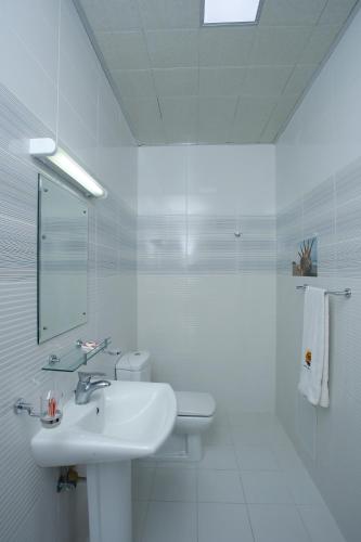 a white bathroom with a sink and a mirror at Bahrain Beach Bay in Az Zallāq