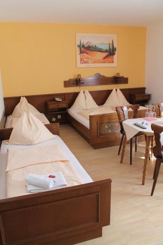 a hotel room with two beds and a table and chairs at Hotel Restaurant Schwartz in Neusiedl am Steinfelde