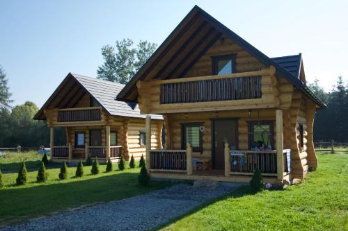 ein Blockhaus mit einer großen Veranda und einem Hof in der Unterkunft Chatki Góralskie in Rabka-Zdrój