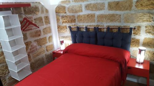 パレルモにあるBrick Apartmentの石壁のベッドルーム1室(赤いベッド1台付)