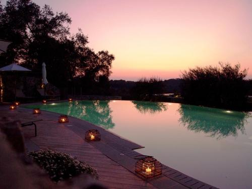 a pool with candles and lights in the water at Torri E Merli Boutique Hotel in Lákka