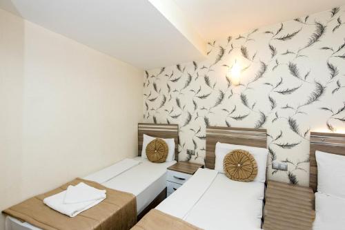 two beds in a small room with a wallpaper at Olimpiyat Hotel Izmir in Izmir