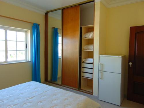 a bedroom with a white bed and a refrigerator at Saraiva's Guest House in Lagos