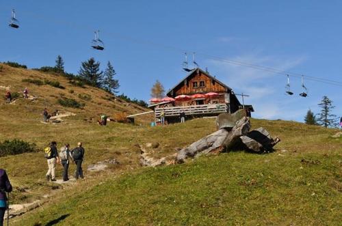 a group of people walking up a hill in front of a house at Frühstückspension Pachler in Gosau