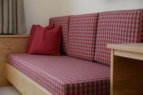 a red and white checkered couch with a red pillow at "Quality Hosts Arlberg Hotel Garni Mössmer" in Sankt Anton am Arlberg