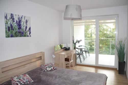 a bedroom with a bed and a desk and a balcony at Kolberg Polanki in Kołobrzeg