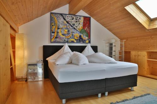 a bedroom with a large white bed with a painting on the wall at Ferienhaus Moidl in Sölden