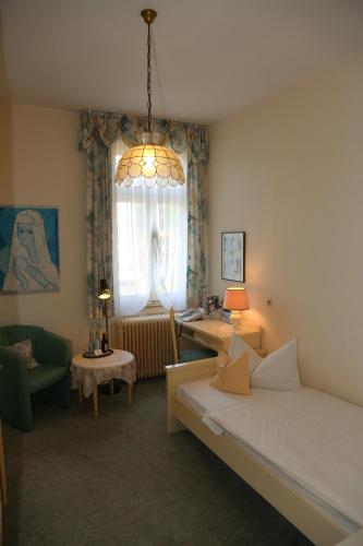 a bedroom with a bed and a table and a window at HOTEL YOGA JASMIN ehemals Hotel Eberhardt-Burghardt in Badenweiler