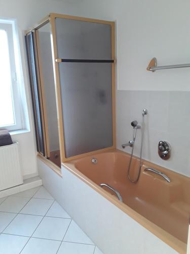 a bathroom with a bath tub with a shower at Orange Sun Apartment in Braunschweig