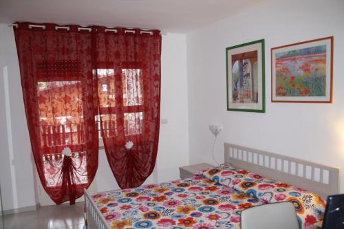 a bedroom with a bed and two windows with red curtains at Affittacamere la Genzianella in Vinadio