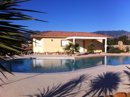 - une piscine en face d'une maison dans l'établissement L'Hacienda Piscine chauffée à 28, spa, boulodrome et court de Tennis privés, 2 villas indépendantes, à Porto-Vecchio