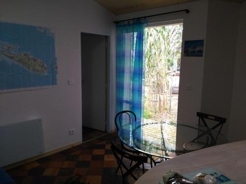 a dining room with a glass table and a window at Les Chênes Bleus in Sainte-Marie-de-Ré