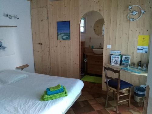 een slaapkamer met een bed en een badkamer met een wastafel bij Les Chênes Bleus in Sainte-Marie-de-Ré