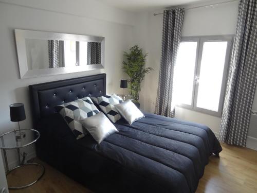 ein Schlafzimmer mit einem großen blauen Bett mit Kissen in der Unterkunft Appartements HEMINGWAY in Avignon