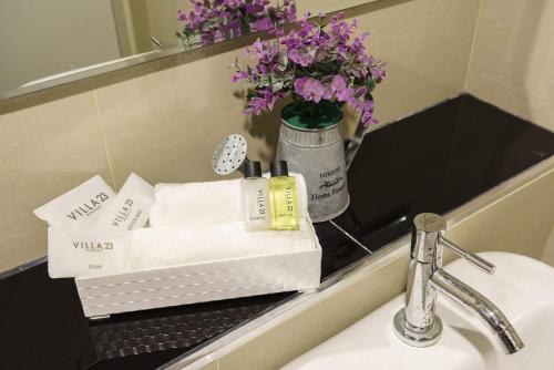een wastafel met handdoeken en een vaas met paarse bloemen bij VILLA23 Residence in Bangkok