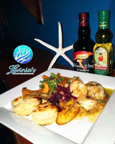 a plate of food with shrimp and vegetables and a bottle of sauce at Miller's Guest House in Buccoo