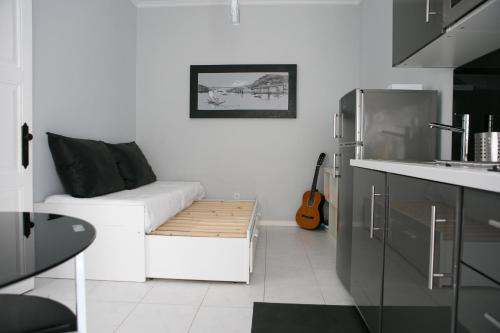 a white living room with a white couch and a guitar at Covelo Apartment in Porto
