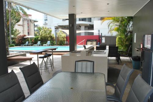 a patio with a table and chairs and a swimming pool at Maroochy Sands Holiday Apartments in Maroochydore