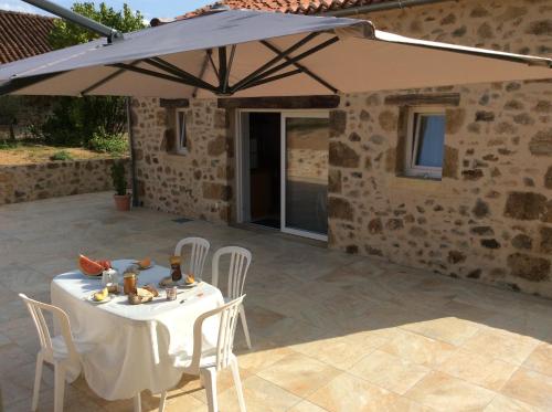 a table and chairs under an umbrella on a patio at Gîte Des Vergnes in Esse