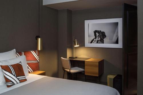 a bedroom with a bed and a desk with a dog on the wall at Hôtel Louvre Piemont in Paris