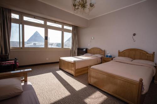 a bedroom with two beds and a view of a pyramid at Guardian Guest House in Cairo