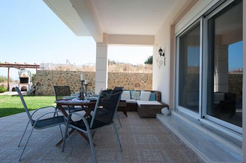 a patio with a table and chairs and a couch at Villa Amfimala in Georgioupolis