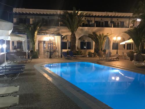 a pool at night with chairs and palm trees at Villa Ilios in Fira