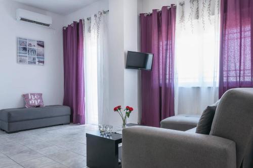 uma sala de estar com cortinas roxas e uma televisão em Nikos Apartments em Agia Marina Nea Kydonias