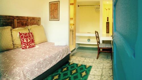 a bedroom with a bed and a chair and a bathroom at Magic Garden House in Cali