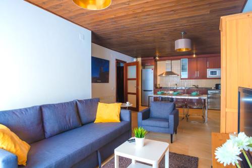 a living room with a blue couch and a kitchen at Ca' la Júlia in Barruera