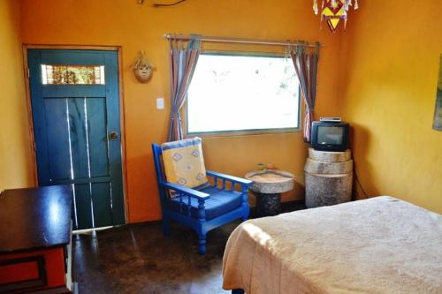 a bedroom with a bed and a blue chair and a window at Puka Wasi Posada in Tarapoto