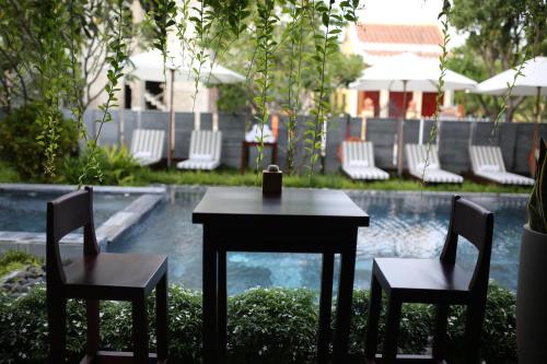a table and two chairs next to a pool at Dai An Phu Villa in Hoi An