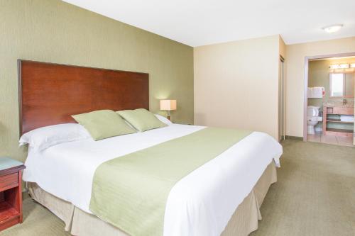 a bedroom with a large white bed with a wooden headboard at Ramada by Wyndham Williams Lake in Williams Lake