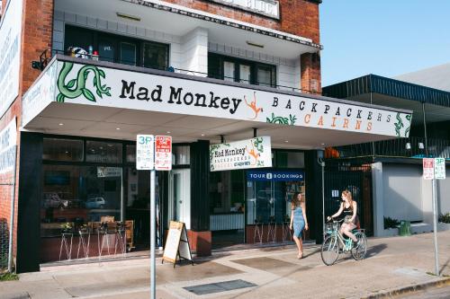a woman riding a bike in front of a restaurant at Mad Monkey Central in Cairns
