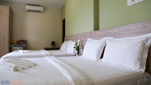 two beds in a hotel room with white sheets and pillows at Mai Vy Hotel Trảng Bàng in Trảng Bàng