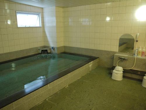 een groot bad in een badkamer met een raam bij Hotel Route-Inn Hakata Ekiminami in Fukuoka