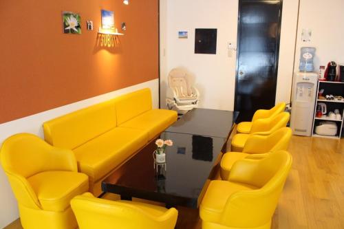 poczekalnia z żółtymi krzesłami i stołem w obiekcie Holiday Homes TSUBOYA 1st w mieście Naha