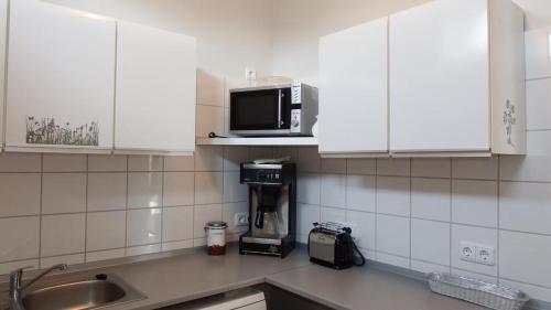 a kitchen with white cabinets and a microwave at Schlei Idyll in Maasholm-Bad