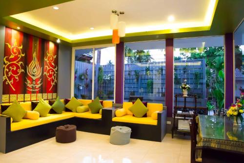 a lobby with a yellow couch and some windows at The Florist Resort in Mae Nam