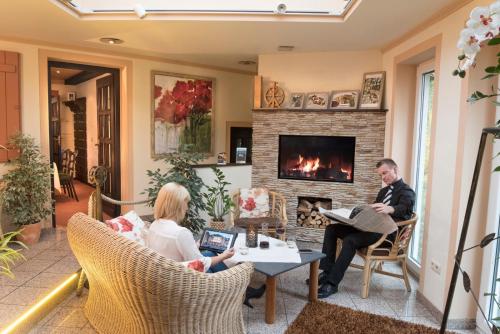 two people sitting in a living room with a fireplace at Hotel Restaurant Lohmühle in Bayreuth