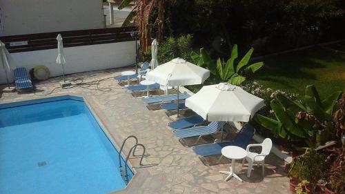 a group of chairs and umbrellas next to a pool at Kozis Hotel Apartments in Polis Chrysochous