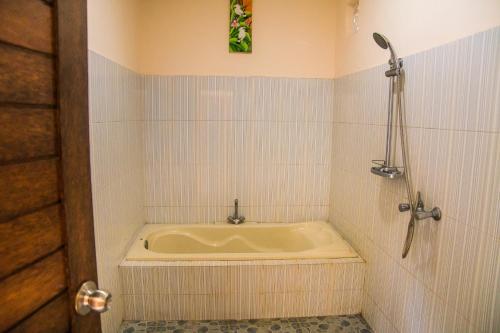 a bath tub in a tiled bathroom with a shower at Pondok Bali in Ubud