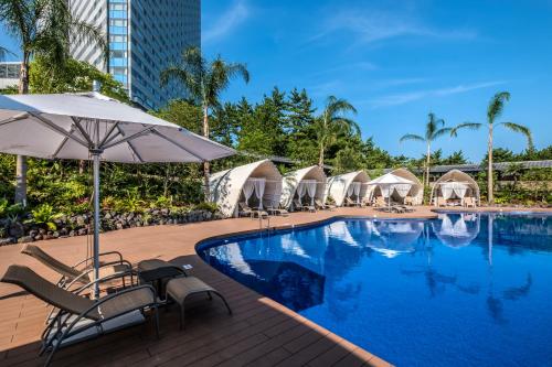 uma piscina num hotel com cadeiras e guarda-sóis em Sheraton Grande Ocean Resort em Miyazaki