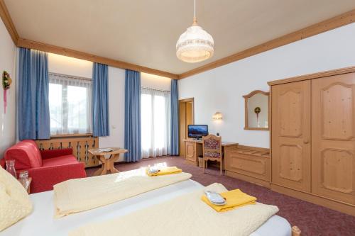 a bedroom with a large bed and a red chair at Landhotel Tharerwirt in Valdaora